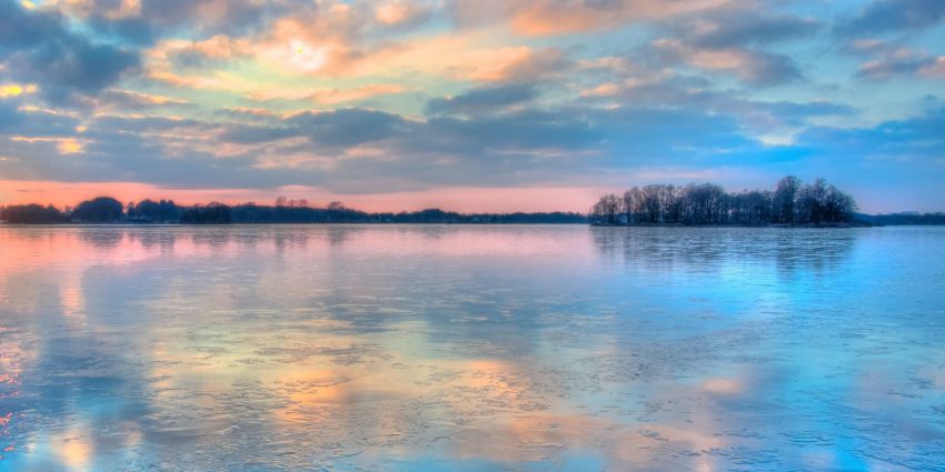 Image capturing techniques for a serene lake reflects colorful clouds at dusk, with an island in the distance, creating a tranquil and picturesque scene. Photography Tips From Industry Experts.