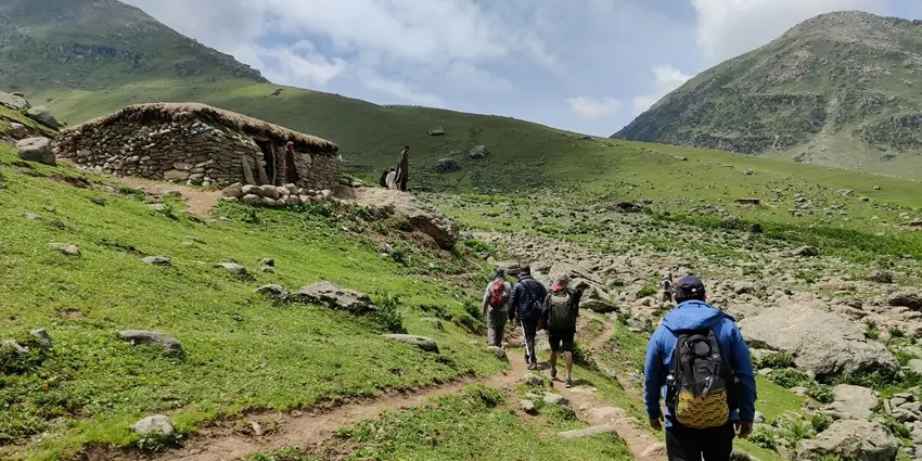 Travelers trekking through lush green mountain trails in India, surrounded by nature.