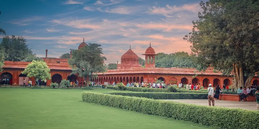 A scenic view of a historic red sandstone monument surrounded by greenery.