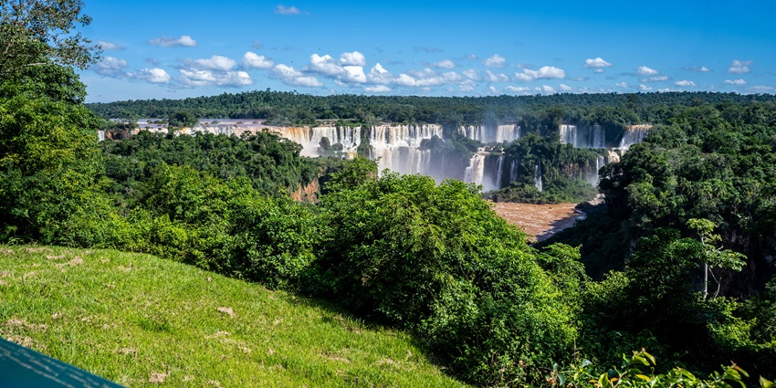 Stunning view of Iguazu Falls in Brazil, surrounded by lush greenery and blue skies.